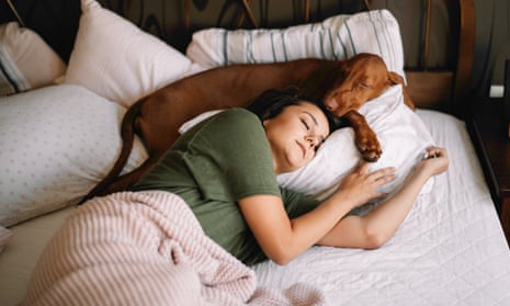 A woman with her dog in her bed