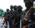 Soldiers in military fatigues and helmets holding assault rifles