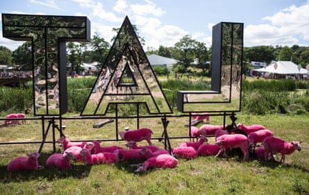 Pink sheep relax beneath the Latitude sign.