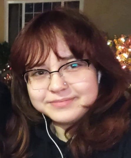 A portrait of a young girl with dark hair and bangs wearing glasses and white earbuds.