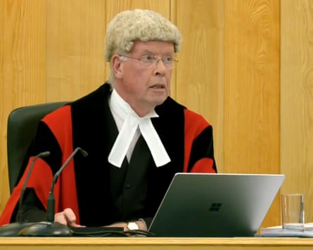 Judge Mark Lucraft KC sits in front of a laptop
