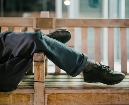 A homeless person sleeps on a bench