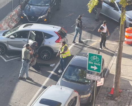 federal agents stand near a man sitting on the ground
