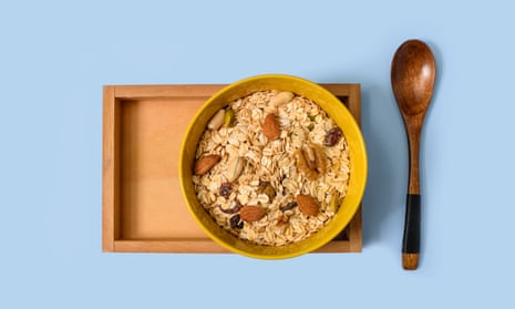 Bowl of muesli and spoon on blue surface