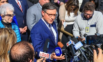 man in a blue suit surrounded by reporters