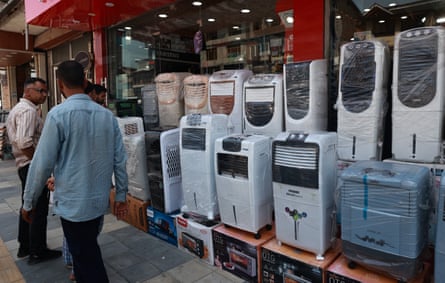 People walk past cooling appliances on sale in a shop