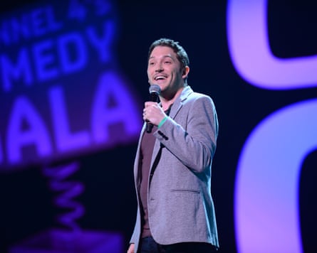 Jon Richardson smiles while speaking into a microphone on stage