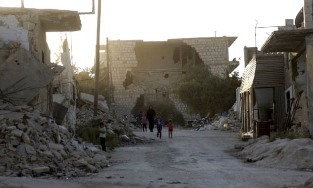 People walk past the rubble of damaged buildings in Maarat al-Nouman