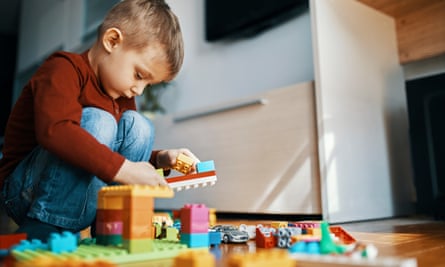 Little boy crouching on the floor at home playing with building bricks