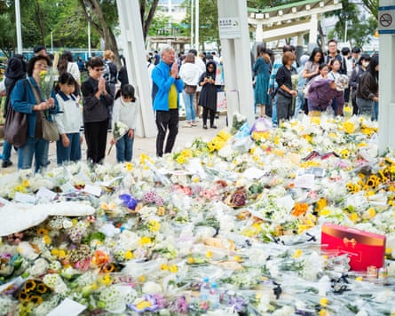 Mourners in front of a mountain of flowers laid in tribute to victims of the fire