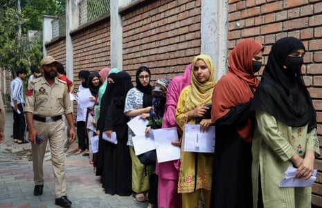 A police officer patrols as students queue outside an examination centre