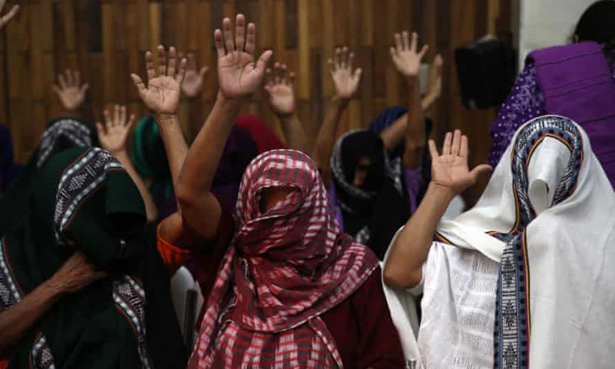 Female victims of sexual slavery covered in scarfs raise their hands at the verdict in the trial of two military officials in Guatemala City.