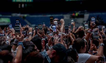 A crowd of fans hold up their phones during a Taylor Swift concert