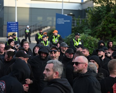 Men, dressed all in black, gathered outside the police station
