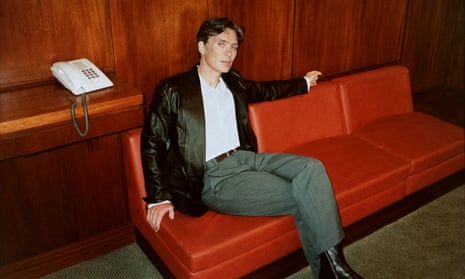 Actor Cillian Murphy sitting on an orange sofa, with an old-fashioned telephone on a desk behind him