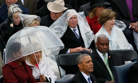 Former president George W Bush keeps covered in the rain at the swearing in of Donald Trump as president.