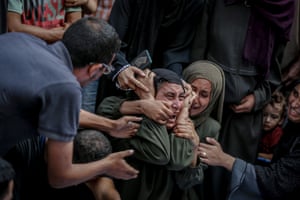 A Palestinian woman overwhelmed with grief, mourning a relative and being comforted by others