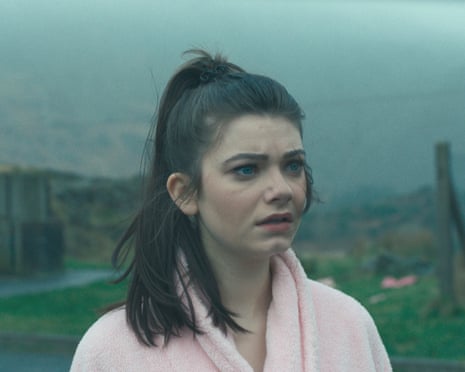 She stands outside in a pink dressing gown, looking worried