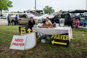 two women sit a table with signs that read ‘need prayer’ and ‘prayer’