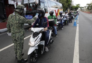 Police check the temperature of motorcyclists in Manila on Friday.