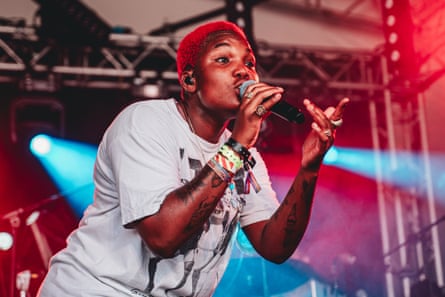 A woman in a white T-shirt singing on a stage.