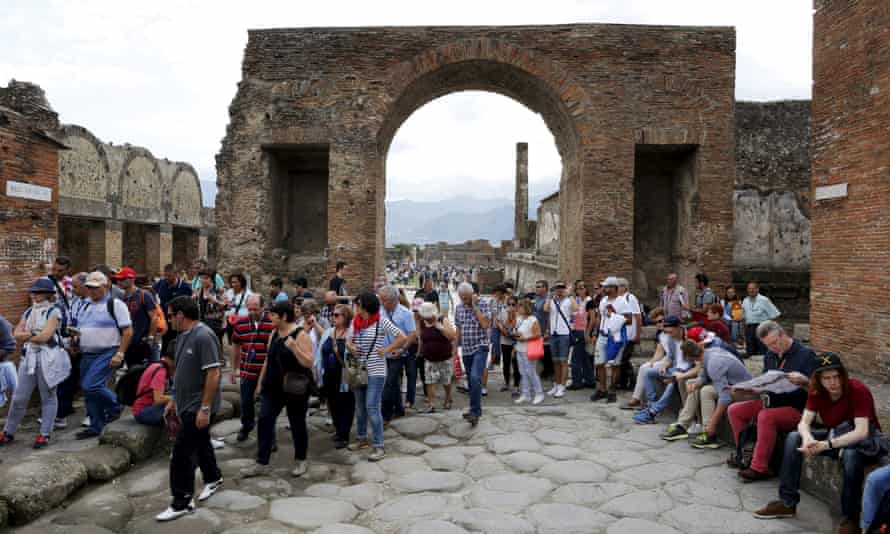 Tourists stand on an ancient Roman cobbled street at Pompeii.