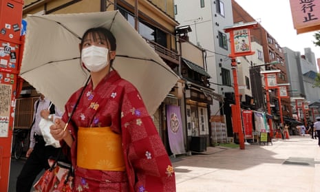 A woman wearing a protective mask walks to a temple in Tokyo's Asakusa district