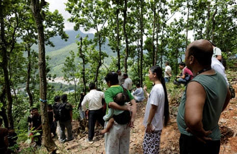 नेपाल के नुवाकोट जिले के त्रिशुली में अचानक आई बाढ़ और भूस्खलन के दो दिन बाद एक झील के किनारे टूटने की चेतावनी मिलने के बाद लोग ऊंची जमीन पर पहुंचकर एक पहाड़ी पर खड़े हो गए।