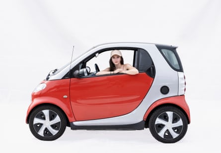 Artist Sofia in a Smart car in Lviv, Ukraine. It is a small red and silver bubble-shaped car