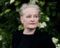 Dorthe Nors looks off to the side, wearing a black top against green foliage