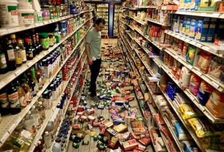 A man looks at grocery items fallen from shelves.