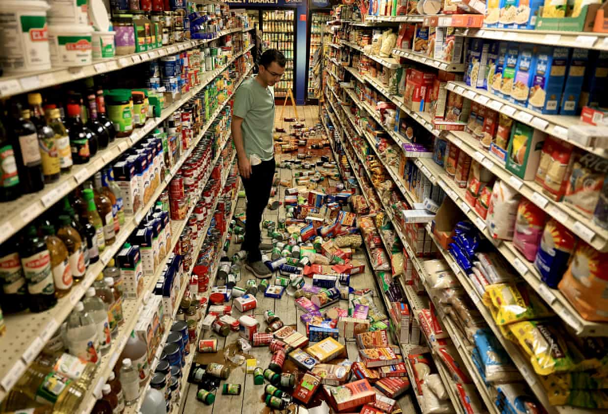 A man looks at grocery items fallen from shelves.