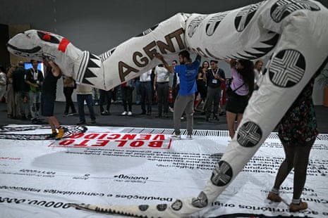 People hold a huge cobra doll during a demonstration demanding climate justice and more protection of indigenous territories at the Blue Zone of COP30.
