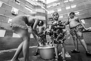 Children playing with a bucket of water in front of a building