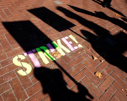 Protesters cast shadows on the sidewalk at the entrance to the UC Berkeley campus during a demonstration.