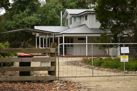 Exterior of a weatherboard house surrounded by trees, seen from the street.