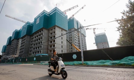 A woman rides a motorbike next to a construction site in Beijing this month.