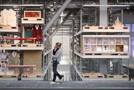 A woman holding a child walks past exhibits at V&A East Storehouse