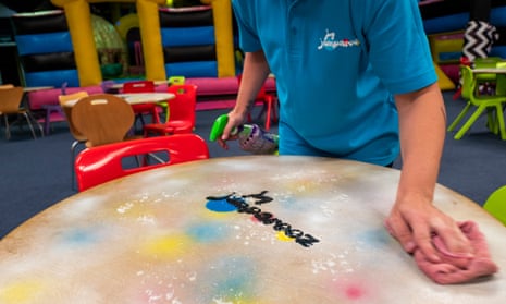 A staff member cleans a table in the seating area at a soft play centre in Manchester