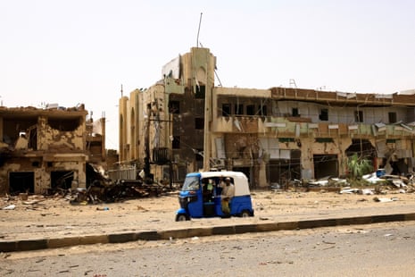 People pass by damaged cars and buildings at the central market in Khartoum.