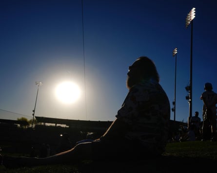 A baseball fan watches players warm up under a bright sun