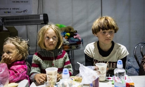 Men, women and children eat and drink at a food tent in Zaporizhzhia catering for evacuees who arrived from Mariupol.