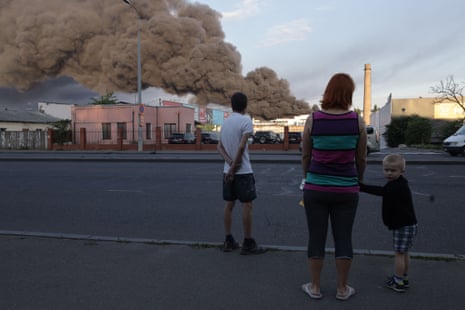 People observe a cloud of smoke from a fire after a missile strike on a warehouse in Odesa on 16 July.