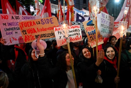 People gather at night in Buenos Aires with protest signs.