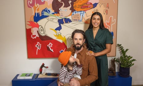 Clarissa and Tim Harris and their child pose in front of their artwork by Mlak in their home