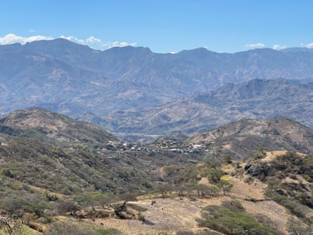 View of a village among green hills and mountains in the distance