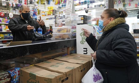 Bodega owner Francisco Marte, left, assists a customer with her purchase 
