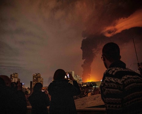 Residents look on as flames and smoke rise from an oil storage facility struck during the US–Israeli military war in Tehran on 7 March.