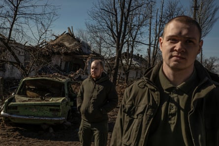 Sasha Semiletov (left) and Valerii Yevsiukov stand among the rubble including a burnt-out car in Zhelanne