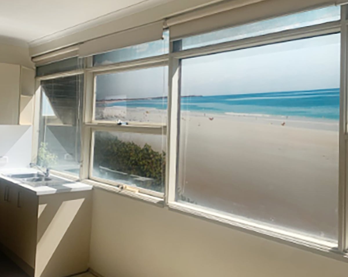 A photo from inside the unit of an apartment showing a mural of a beach out the window